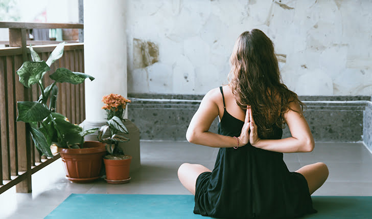 Mujer haciendo yoga en el balcón